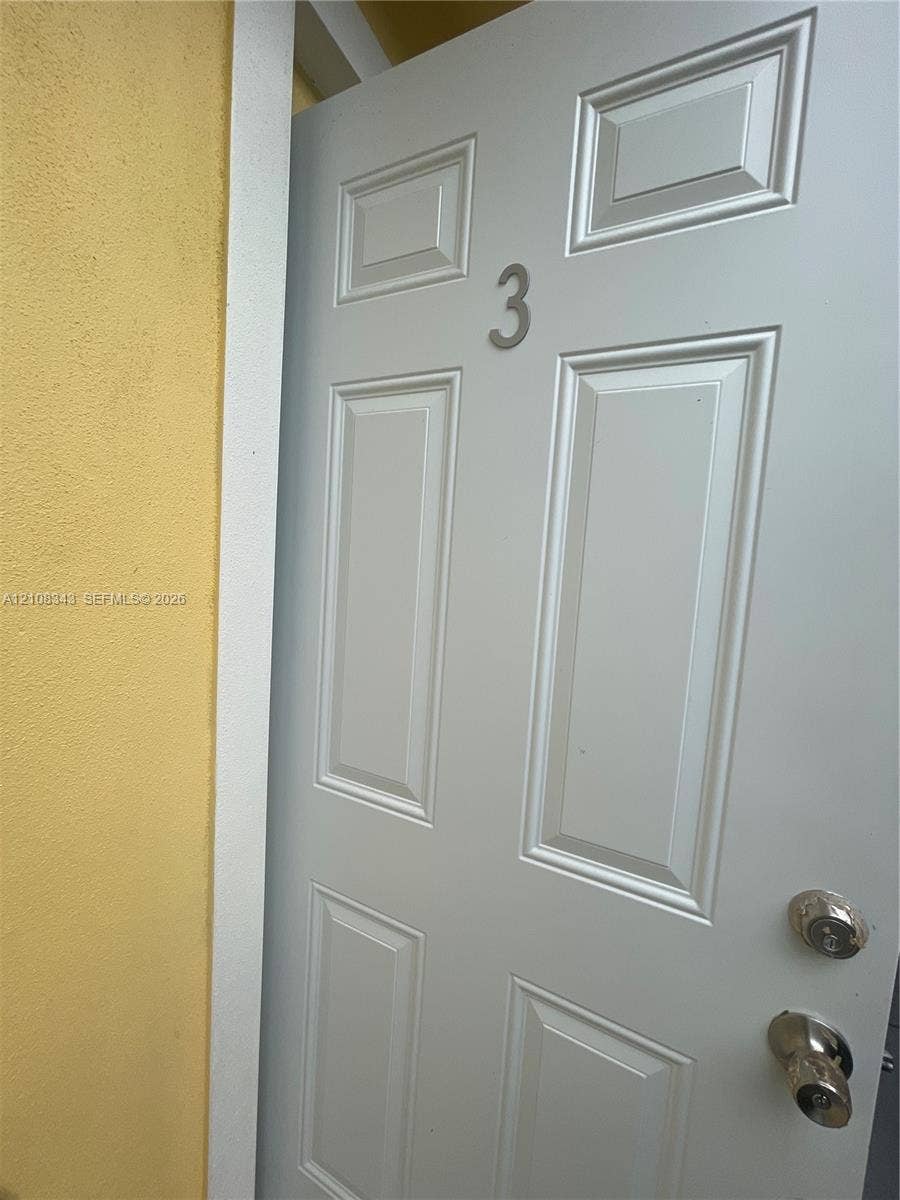 1935 Liberty Street, #3, Hollywood, Hollywood, FL 33020 Panelled door featuring a metallic numeral, polished hardware, and a white casing against a stucco wall