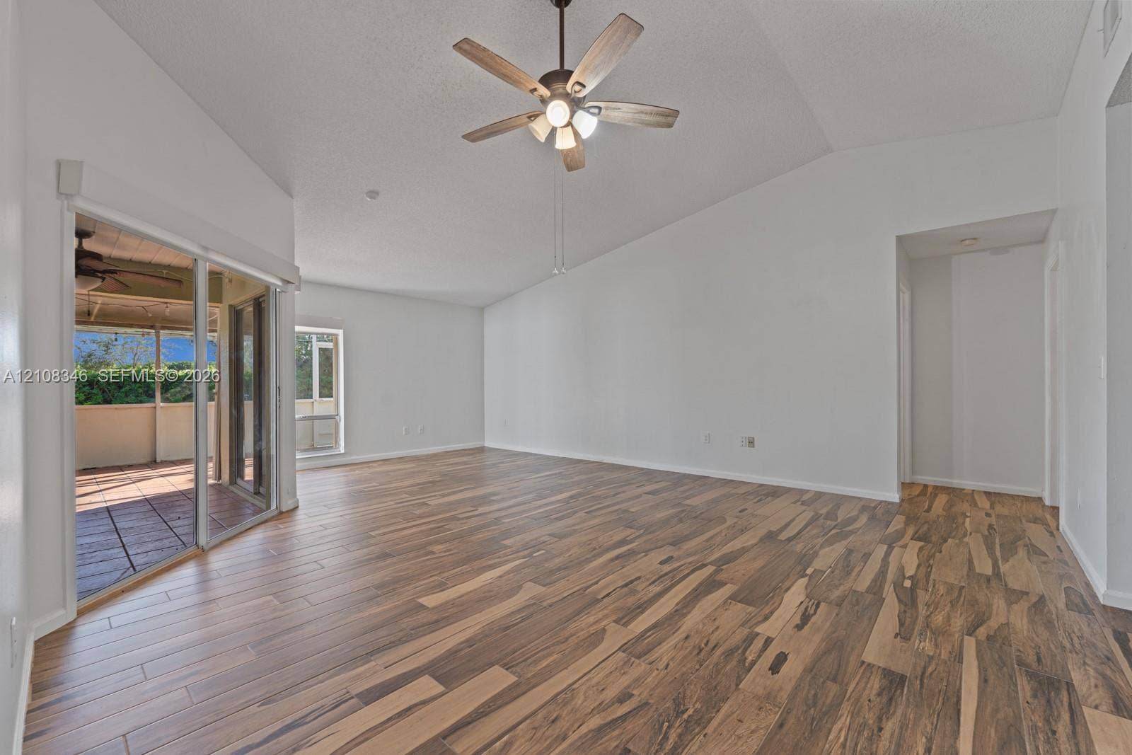 2530 SE 7th Place, Homestead, FL 33033 Vaulted ceilings, wood-finish flooring, ceiling fan with integrated lighting, and sliding glass doors