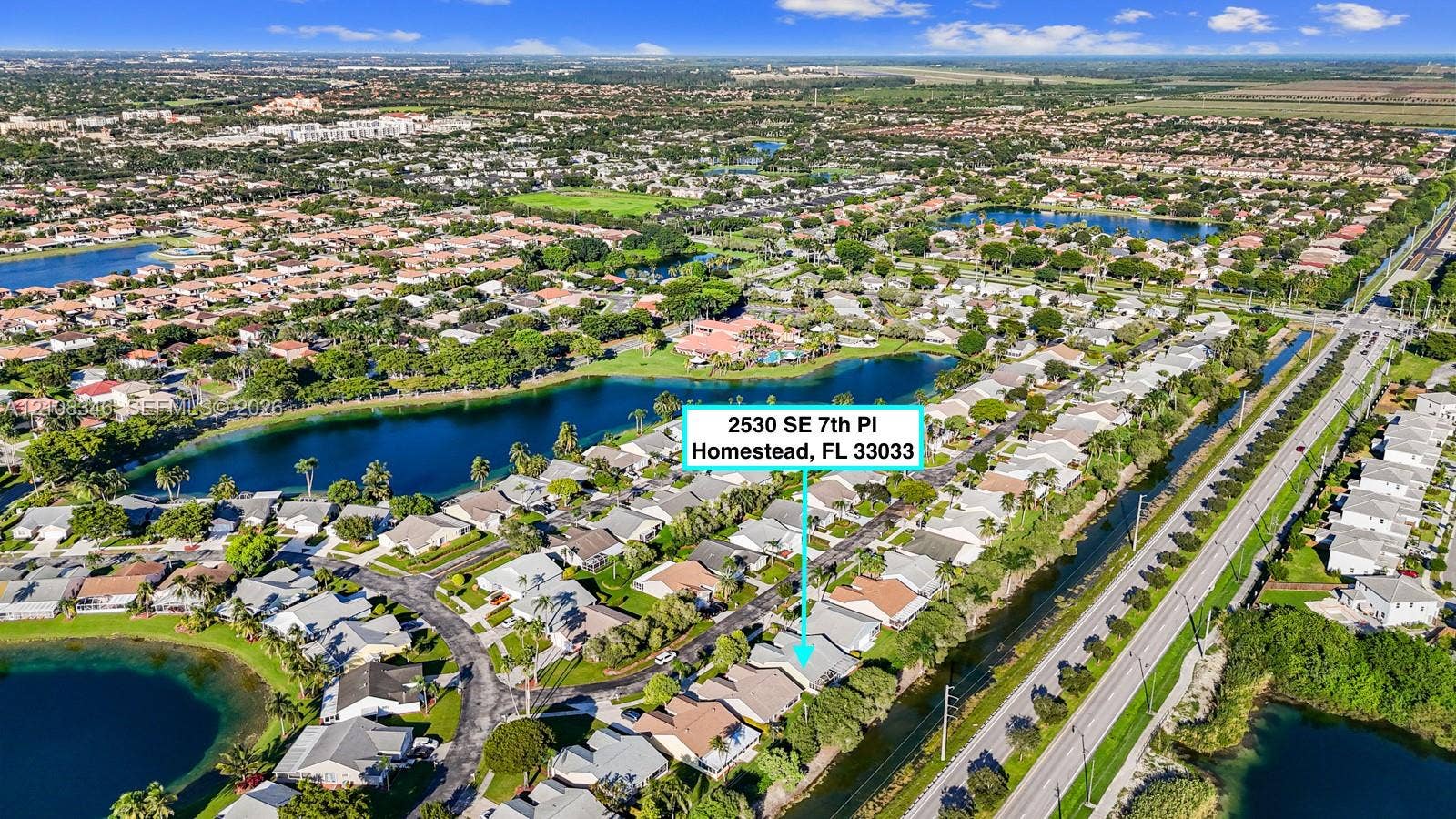 2530 SE 7th Place, Homestead, FL 33033 Aerial perspective of a residential property situated in a planned community featuring multi-acre lakes and dense perimeter landscaping