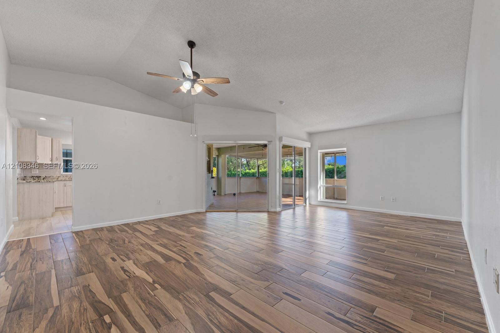 2530 SE 7th Place, Homestead, FL 33033 Living area featuring vaulted ceilings, wood-finish tile flooring, a ceiling fan with integrated lighting, and glass sliding doors