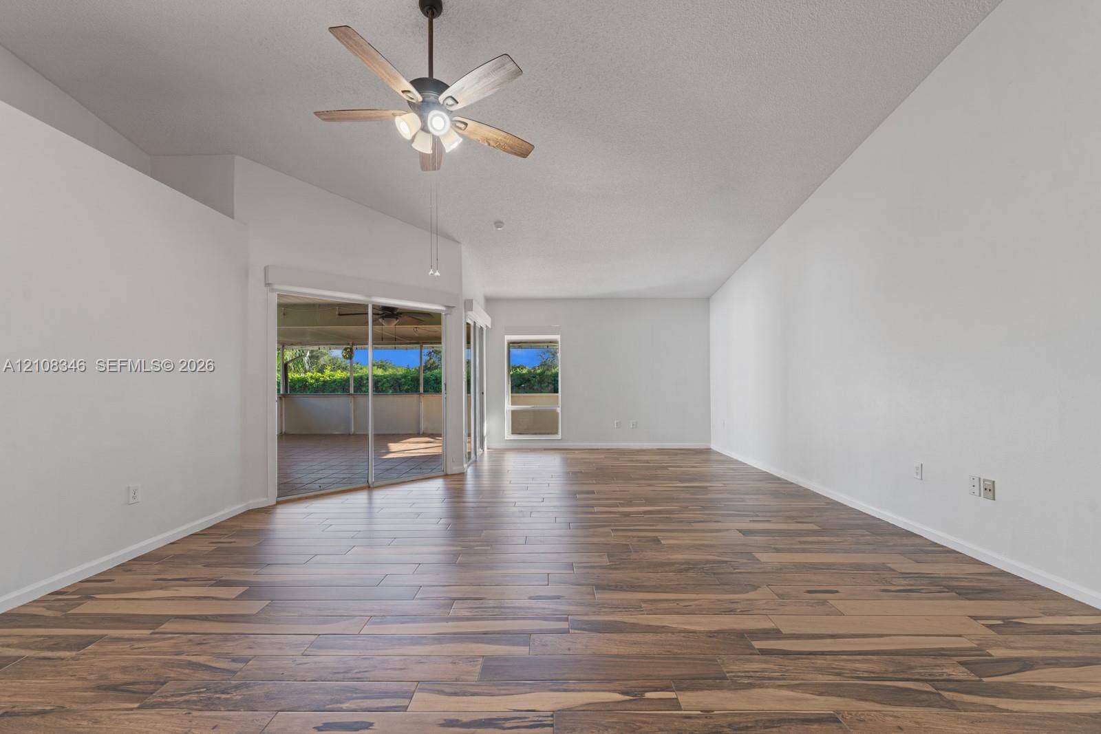 2530 SE 7th Place, Homestead, FL 33033 Vaulted ceilings featuring a five-blade ceiling fan with integrated lighting, wood-finish flooring, and sliding glass doors