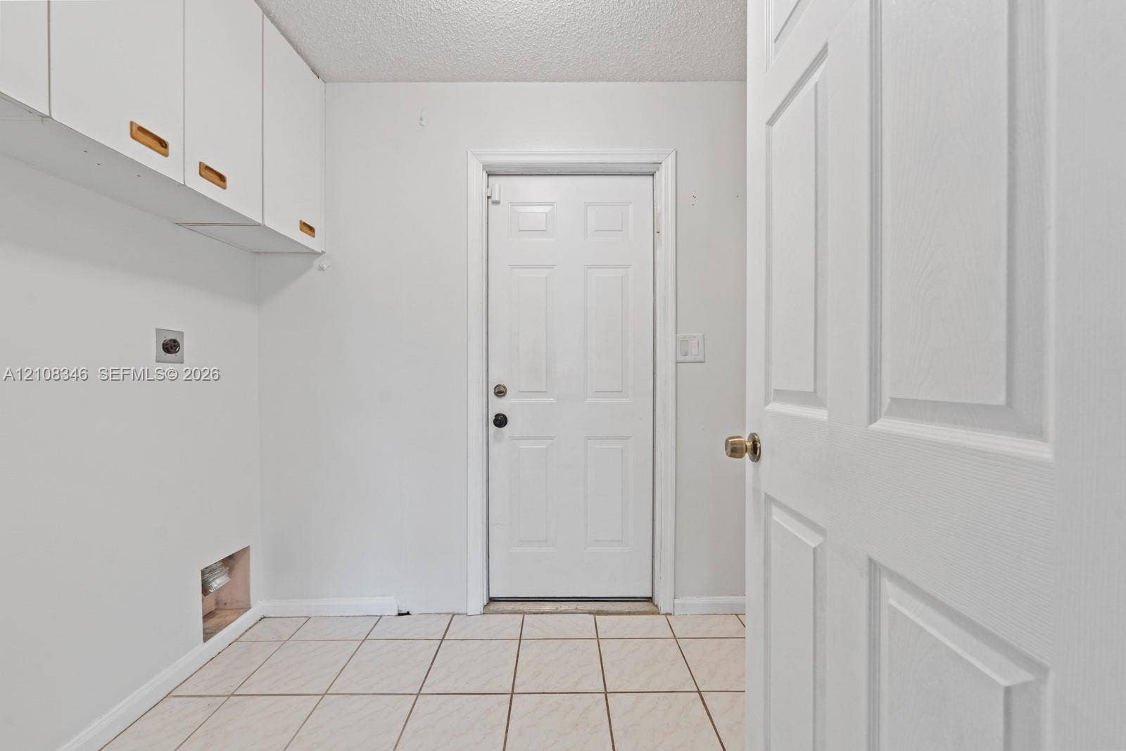 2530 SE 7th Place, Homestead, FL 33033 Utility space featuring white wall-mounted cabinetry, tile flooring, and a six-panel exterior door