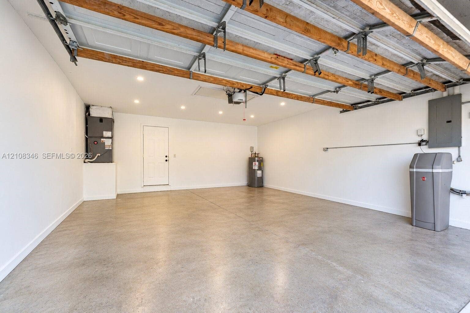 2530 SE 7th Place, Homestead, FL 33033 Spacious garage featuring concrete flooring, recessed lighting, exposed wood ceiling rafters, a dedicated water heater, and an integrated water softening system