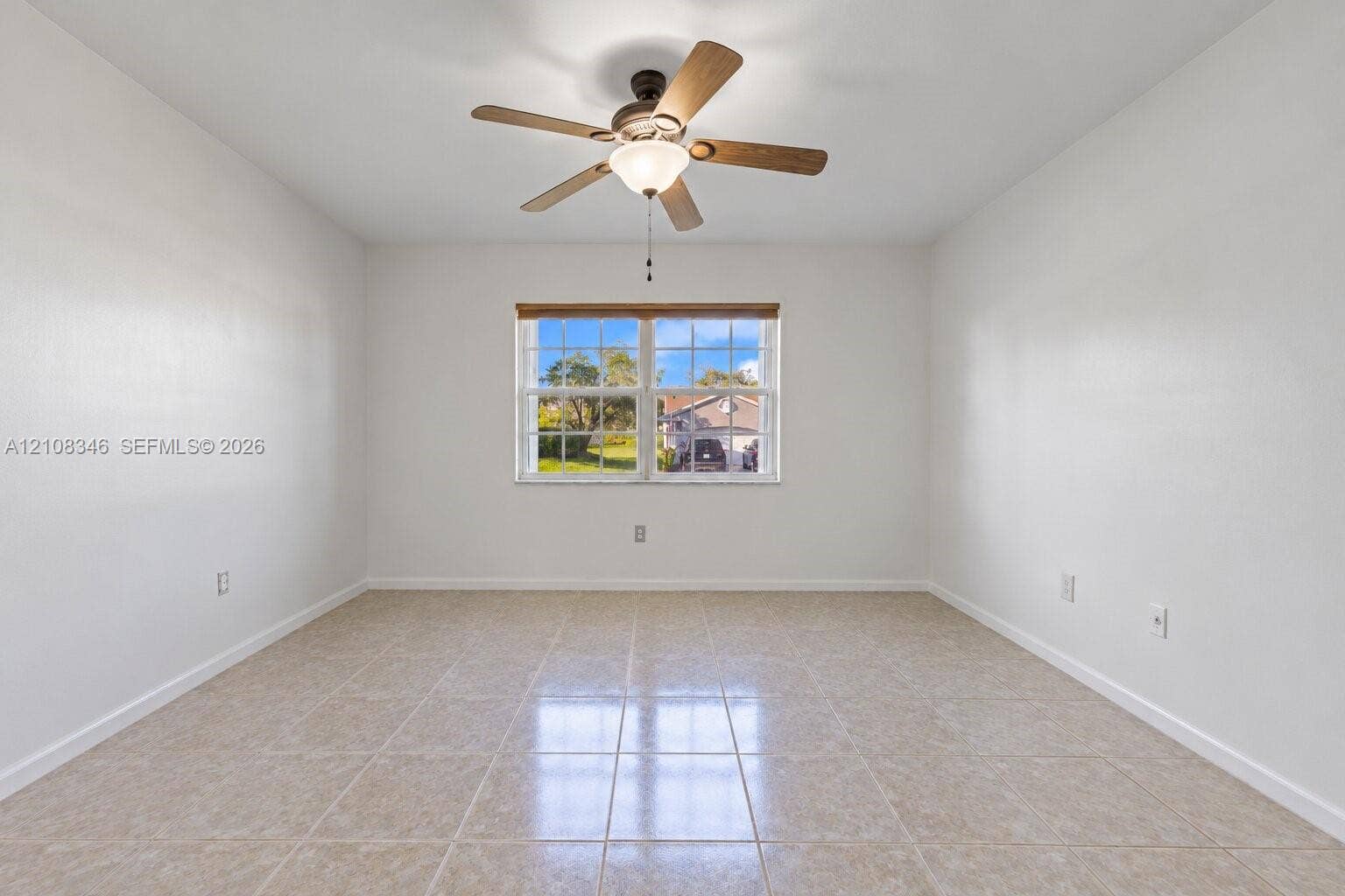 2530 SE 7th Place, Homestead, FL 33033 Room featuring ceramic tile flooring, a multi-pane window with a light-filtering shade, and a central ceiling fan with integrated lighting