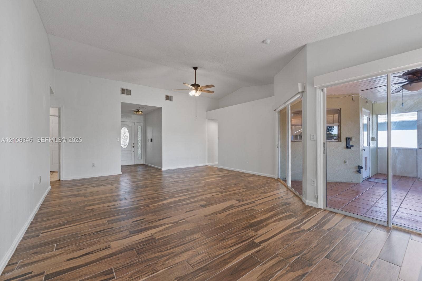 2530 SE 7th Place, Homestead, FL 33033 Open floor plan featuring vaulted ceilings, wood-finish tile flooring, ceiling fan with integrated lighting, and glass sliding doors