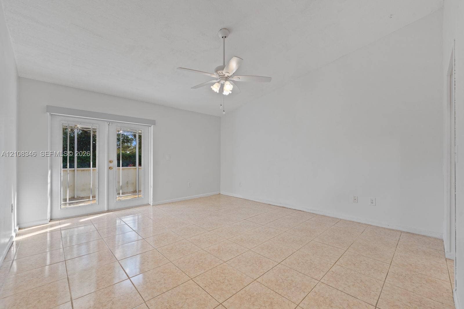 2530 SE 7th Place, Homestead, FL 33033 Spacious interior featuring neutral ceramic tile flooring, vaulted ceilings, a white ceiling fan with integrated lighting, and full-glass French doors