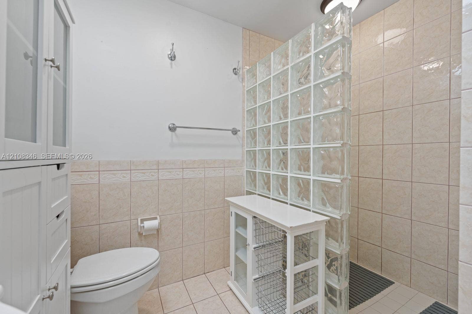 2530 SE 7th Place, Homestead, FL 33033 Glass block privacy partition, neutral wall-to-wall ceramic tile, built-in floor-to-ceiling cabinetry, and wall-mounted metal hardware