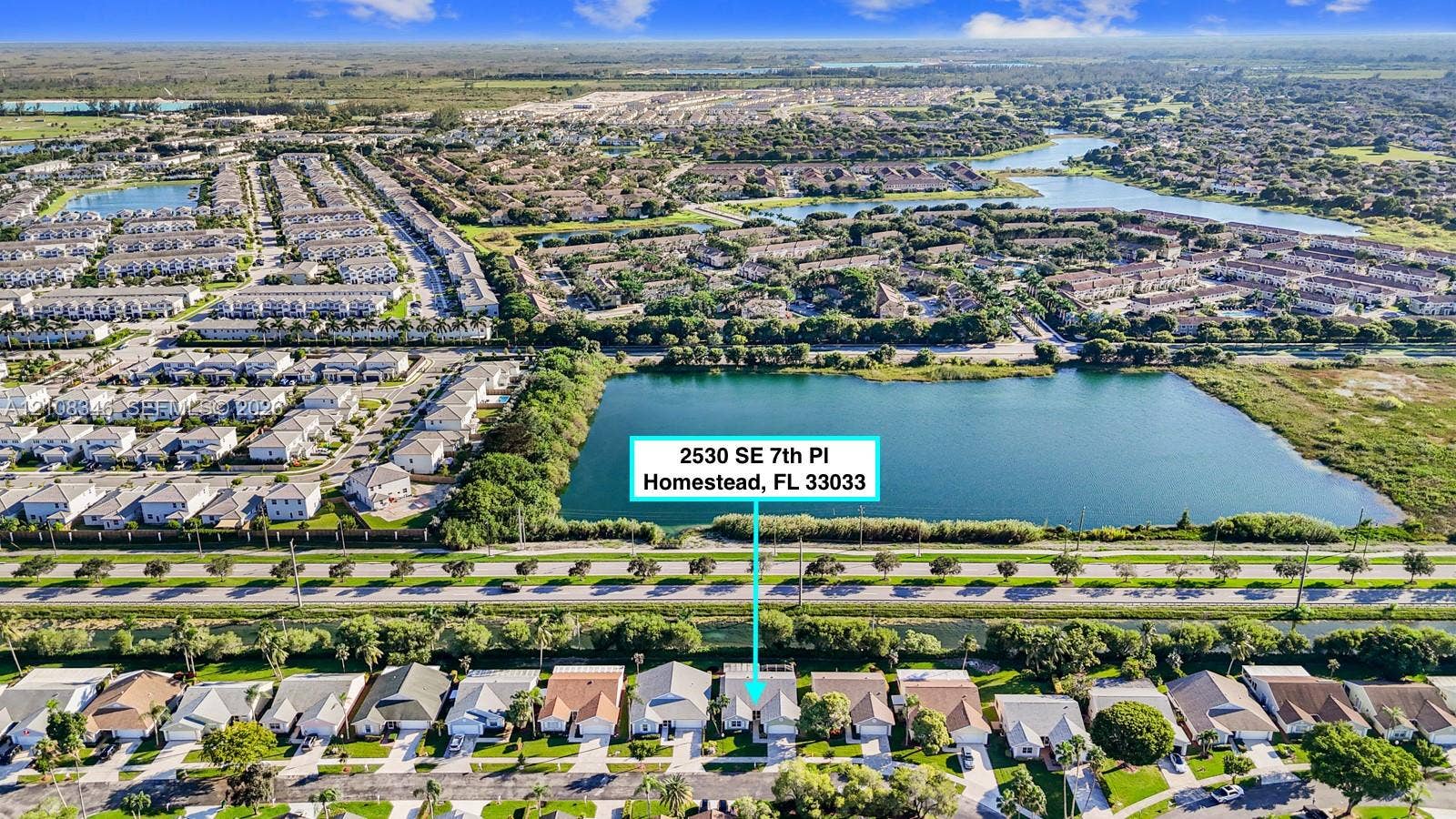 2530 SE 7th Place, Homestead, FL 33033 Aerial perspective featuring a single-family residence situated on a lot bordering a large lake with expansive surrounding water features and lush landscaping