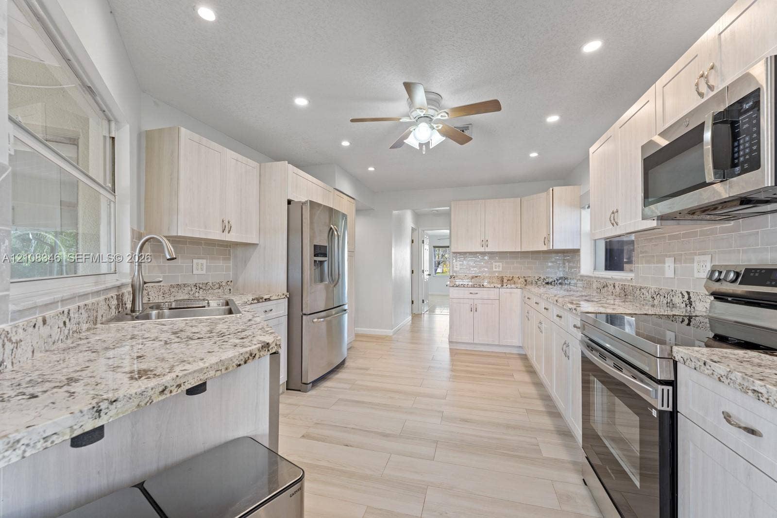 2530 SE 7th Place, Homestead, FL 33033 Kitchen featuring light-toned wood cabinetry, stone countertops, stainless steel appliances, subway tile backsplash, and wood-tile flooring