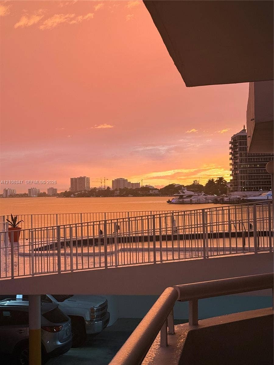 Elevated balcony featuring a white metal railing and direct water frontage, highlighted by sunset scenery over the horizon