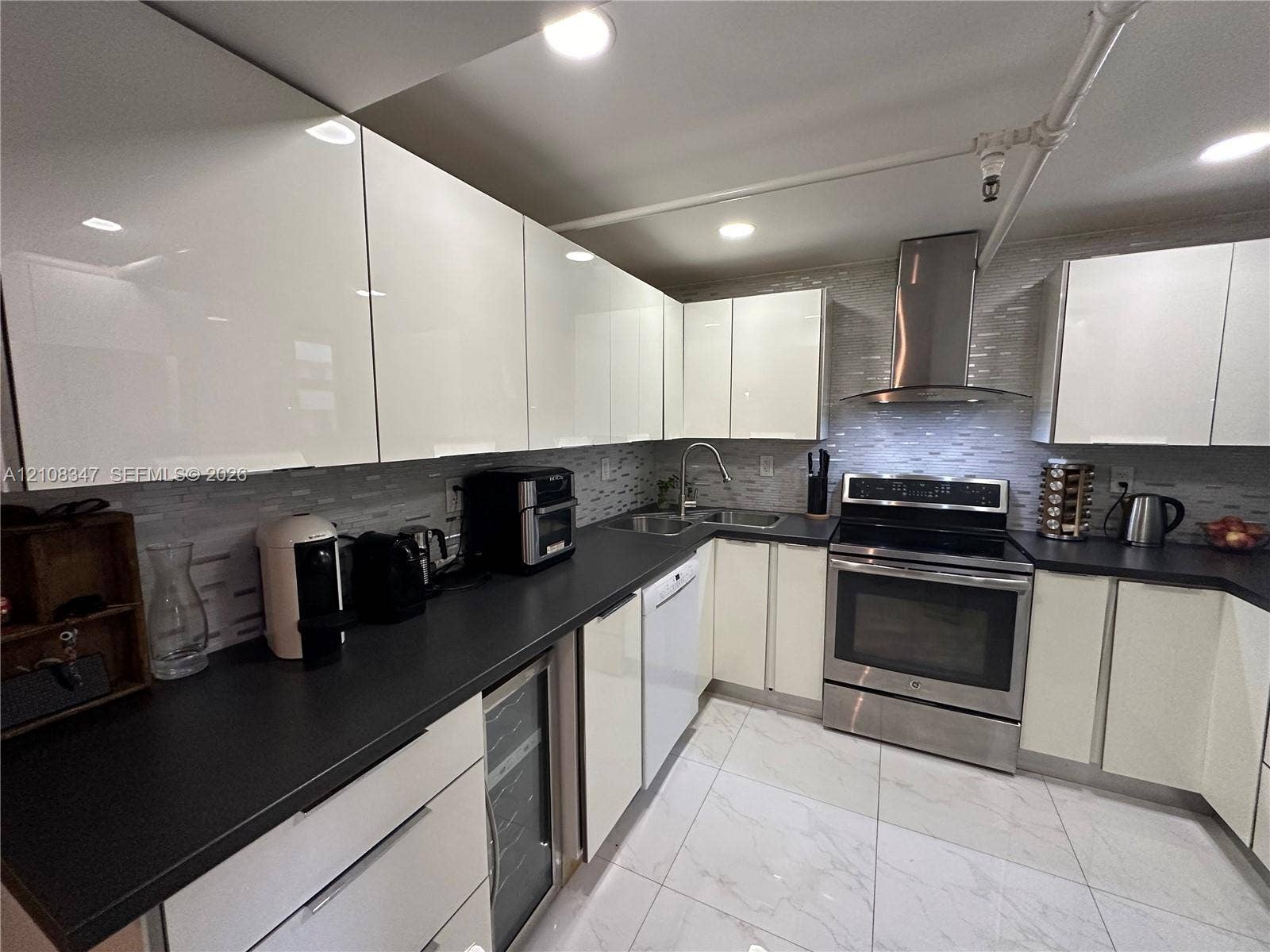 stainless steel chimney-style range hood, integrated wine refrigerator, and stone-finish tile flooring