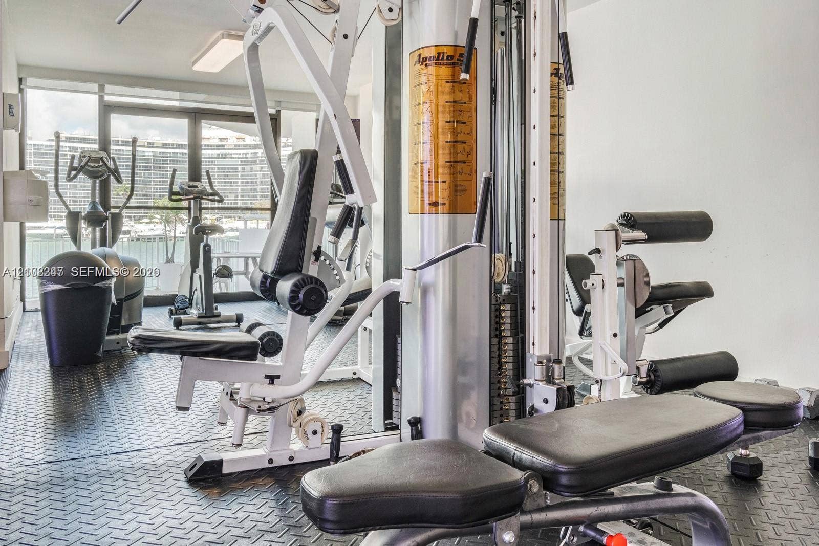 Fitness center featuring black diamond-plate rubber flooring and floor-to-ceiling glass sliding doors