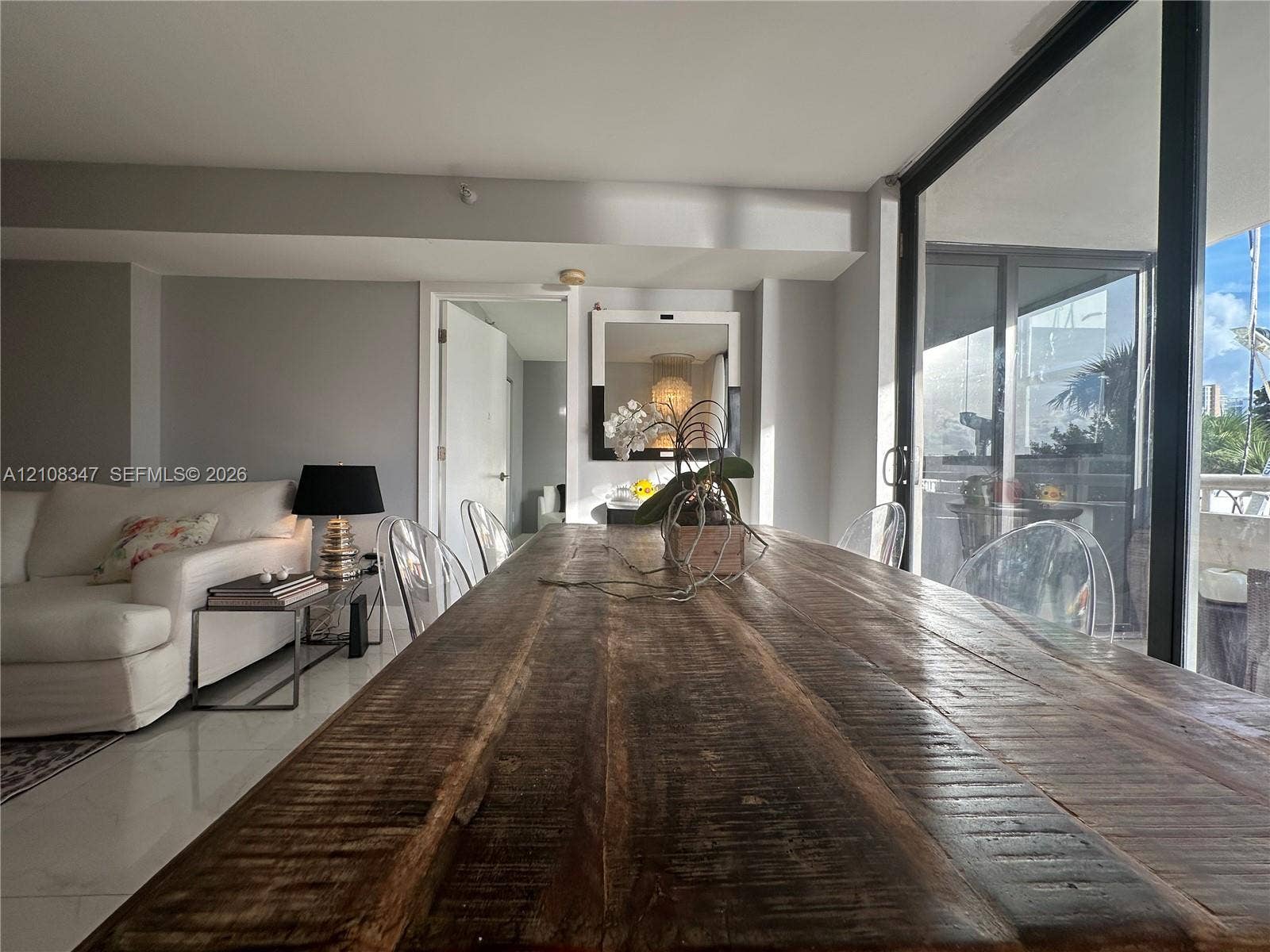 Neutral interior featuring polished tile flooring, full-height glass sliding doors, and a wall-mounted mirror with a black frame