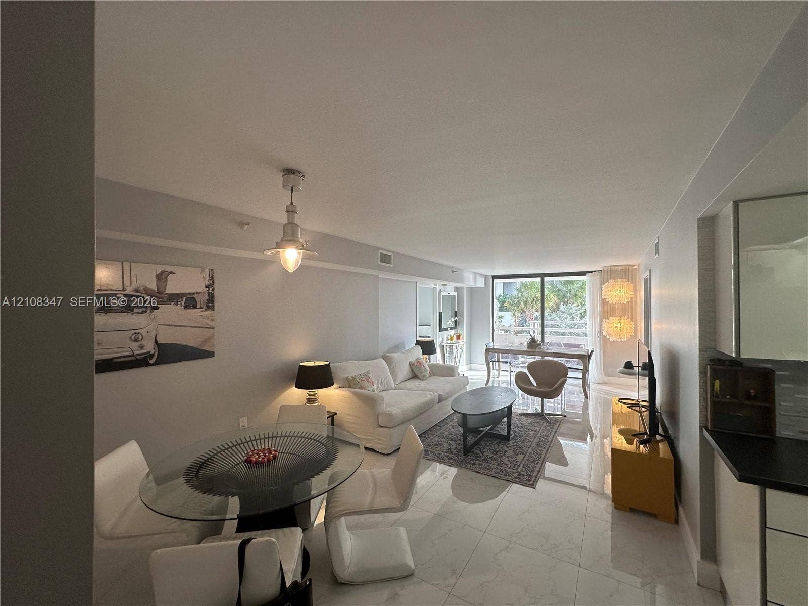 Open-concept living space featuring large-format tile flooring, industrial-style pendant lighting, and floor-to-ceiling glass doors
