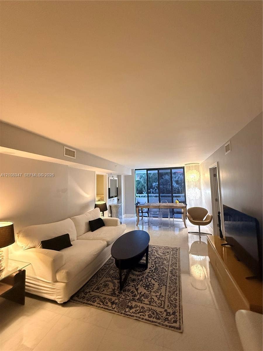 Open-concept living space featuring high-gloss tile flooring, floor-to-ceiling sliding glass doors, and recessed lighting