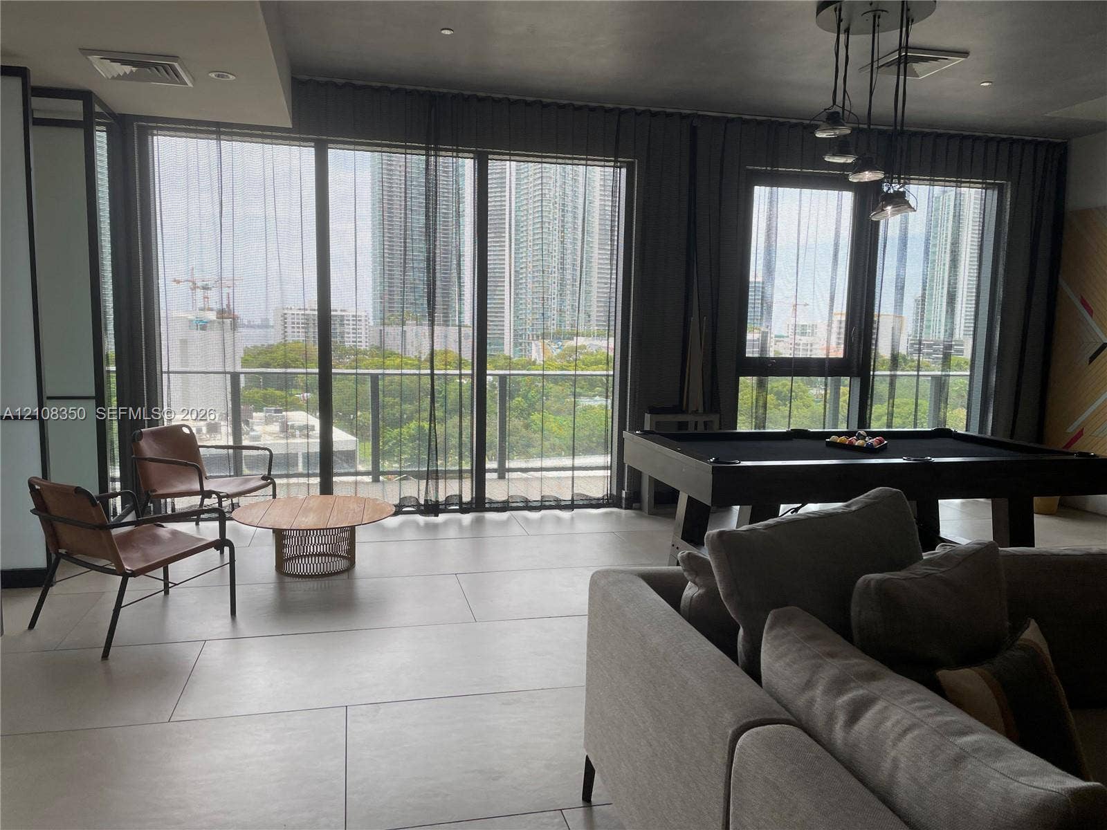 121 NE 34th Street, #1403, Miami, Miami, FL 33137 Floor-to-ceiling glass panel windows, large-format tile flooring, multi-pendant metal lighting fixture, and a railed balcony
