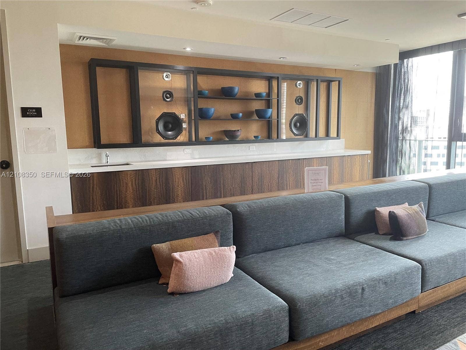121 NE 34th Street, #1403, Miami, Miami, FL 33137 Custom built-in cabinetry with wood-finish lower panels, recessed shelving, integrated speakers, and a solid-surface countertop