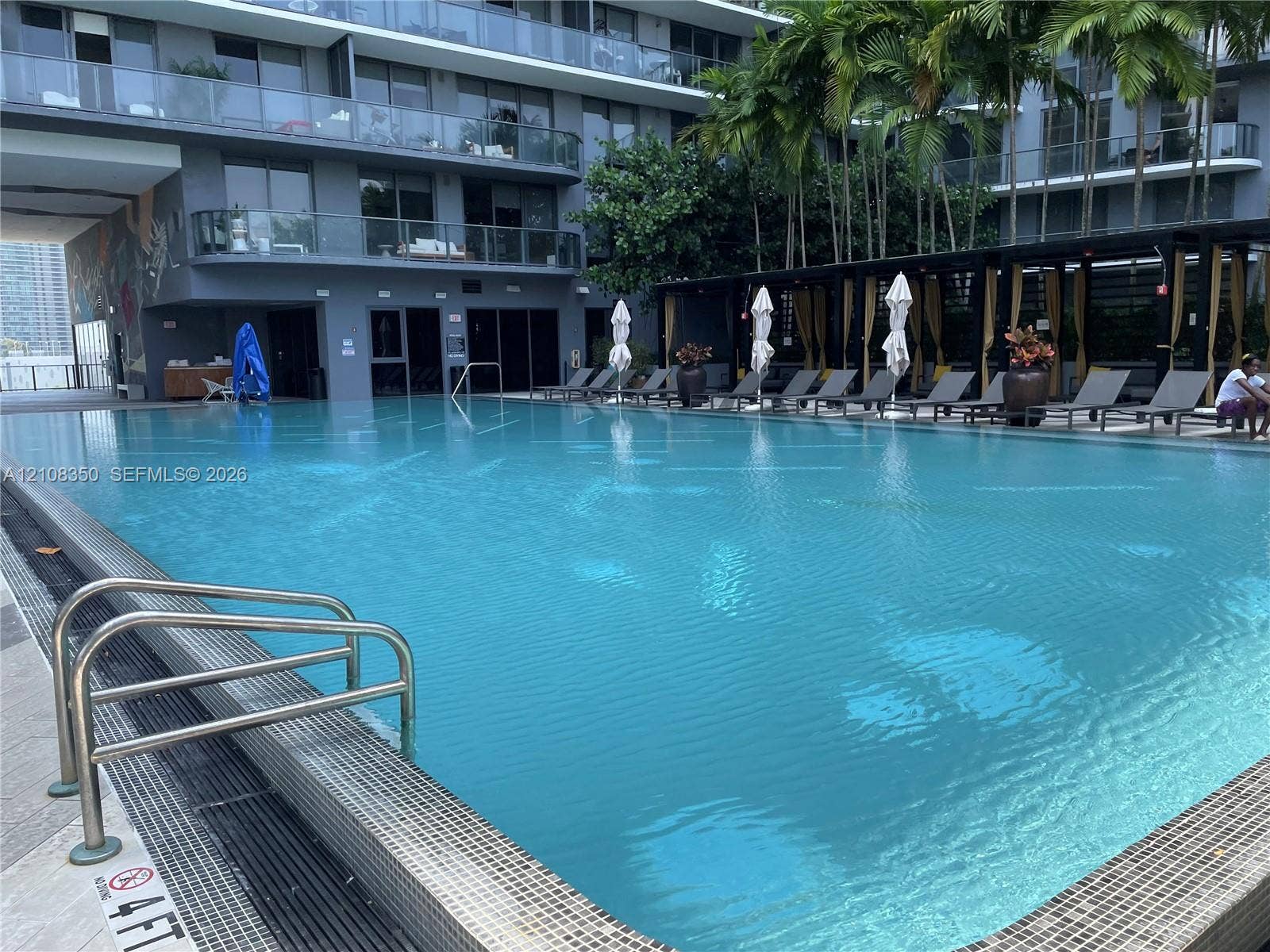 121 NE 34th Street, #1403, Miami, Miami, FL 33137 Swimming pool with tile edging, submerged metal ladder, stone pool deck, and covered pergola area