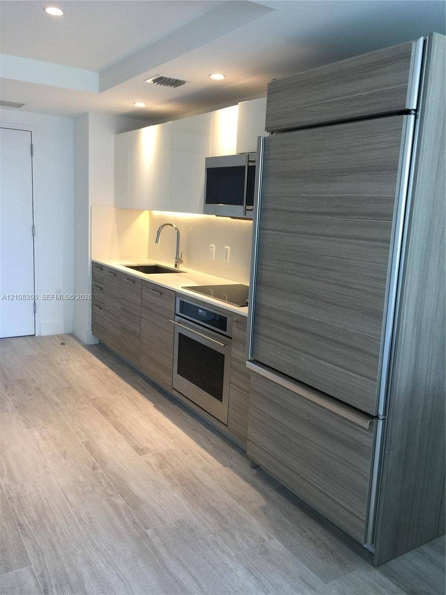 121 NE 34th Street, #1403, Miami, Miami, FL 33137 Kitchen featuring flat-panel wood-finish cabinetry, integrated refrigerator, stone countertop, stainless steel oven, and recessed lighting