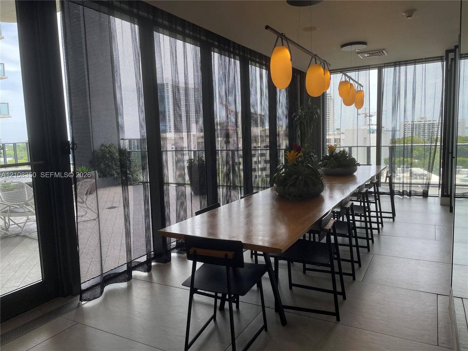 121 NE 34th Street, #1403, Miami, Miami, FL 33137 Floor-to-ceiling glass paneling with sliding door access to a balcony, large-format tile flooring, and custom multi-pendant lighting fixture
