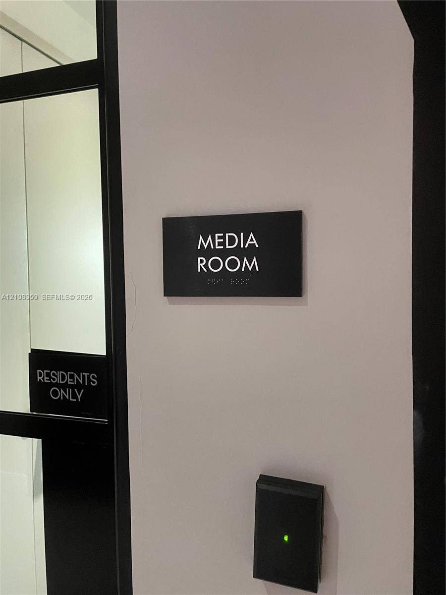 121 NE 34th Street, #1403, Miami, Miami, FL 33137 Media room featuring black signage, electronic key fob access control, and glass-paneled entry door
