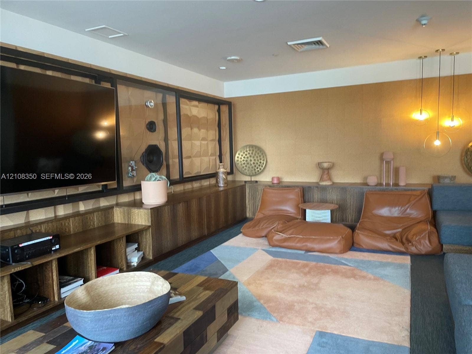 121 NE 34th Street, #1403, Miami, Miami, FL 33137 Custom built-in wood cabinetry, three-pendant modern lighting, integrated media wall with geometric wall panels, and warm-toned textured wall finish