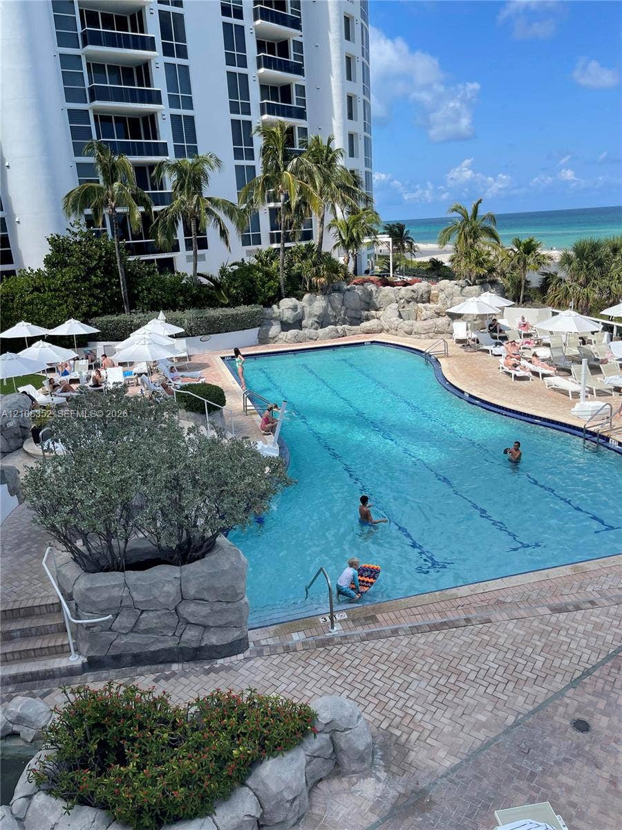 18001 Collins Avenue, #907, Sunny Isles Beach, FL 33160 Swimming pool with lane markings, natural stone rockery accents, brick-paver pool deck, and coastal water horizon