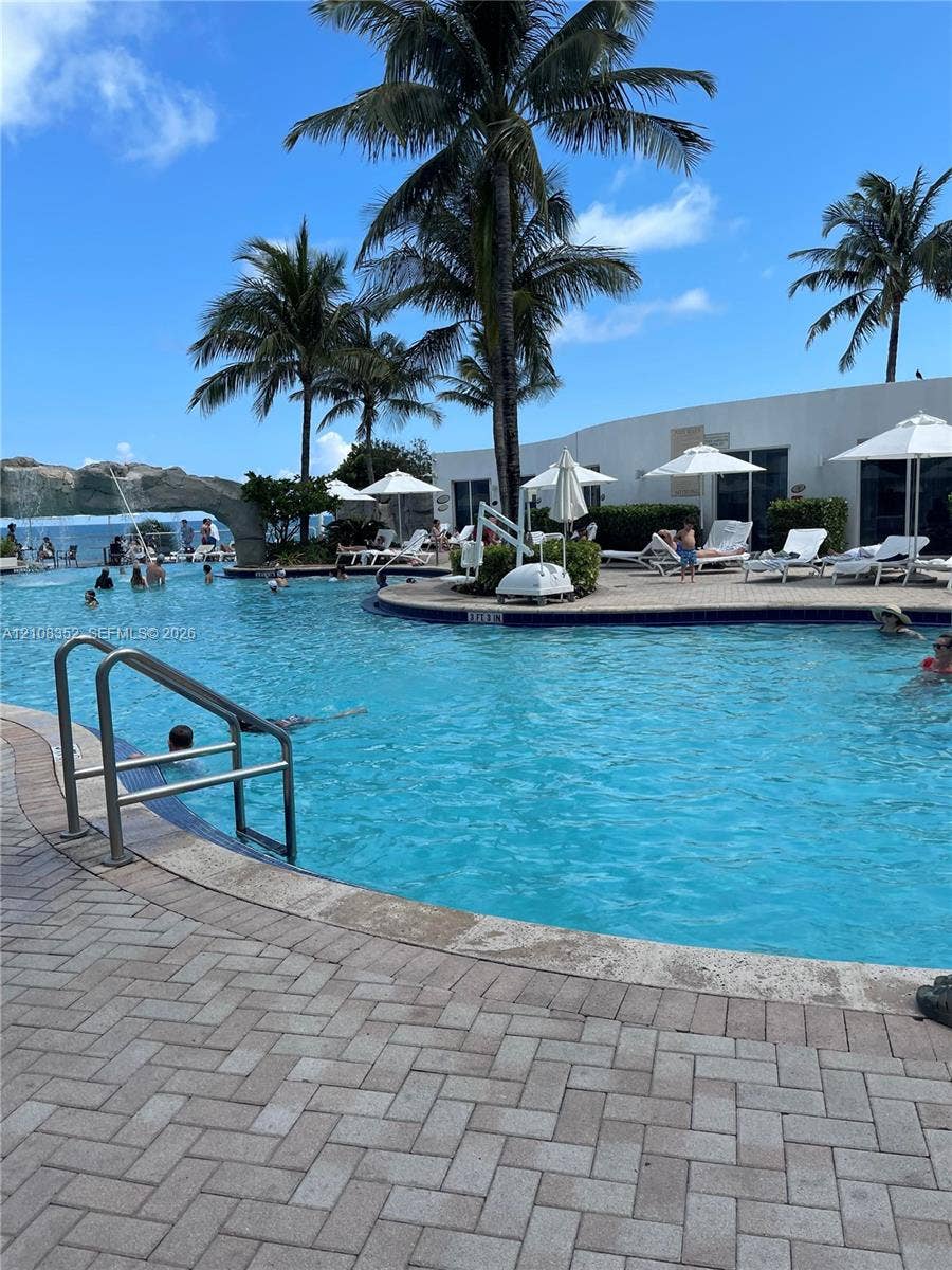 18001 Collins Avenue, #907, Sunny Isles Beach, FL 33160 Swimming pool with a stone water feature, paved deck, and mature palm trees