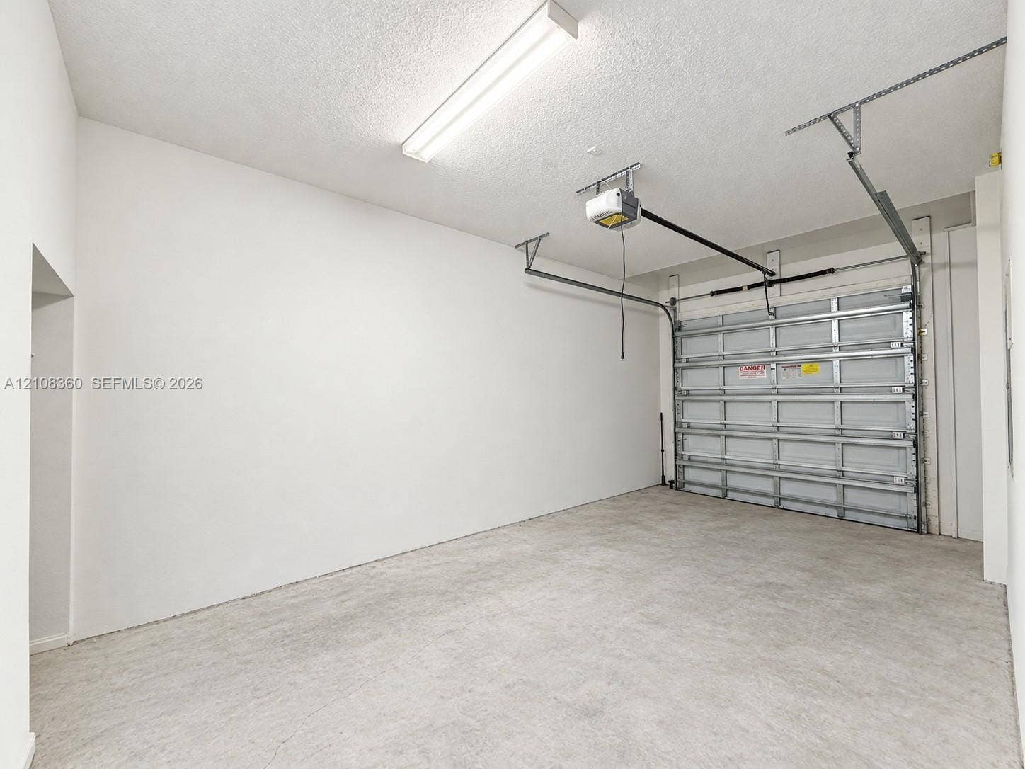 4608 Tara Cove Way, #4608, West Palm Beach, West Palm Beach, FL 33417 Attached garage featuring a concrete floor, high-clearance ceiling, integrated automatic door opener, and linear fluorescent lighting