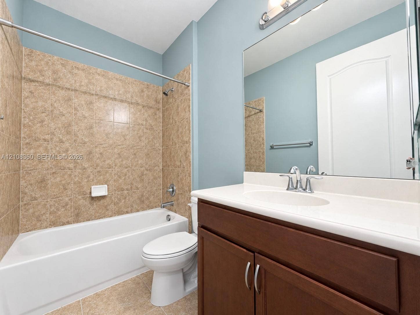 4608 Tara Cove Way, #4608, West Palm Beach, West Palm Beach, FL 33417 Bathroom featuring a white porcelain tub, wood-finish vanity with a solid-surface countertop, integrated sink, and large wall-mounted mirror