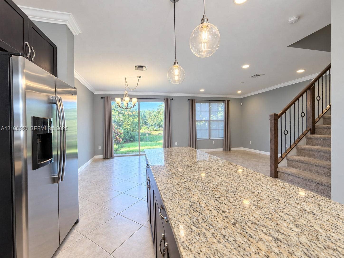4608 Tara Cove Way, #4608, West Palm Beach, West Palm Beach, FL 33417 Kitchen featuring a sprawling stone-surface island, dark-toned cabinetry, stainless steel refrigerator, glass pendant lighting, and neutral floor tile