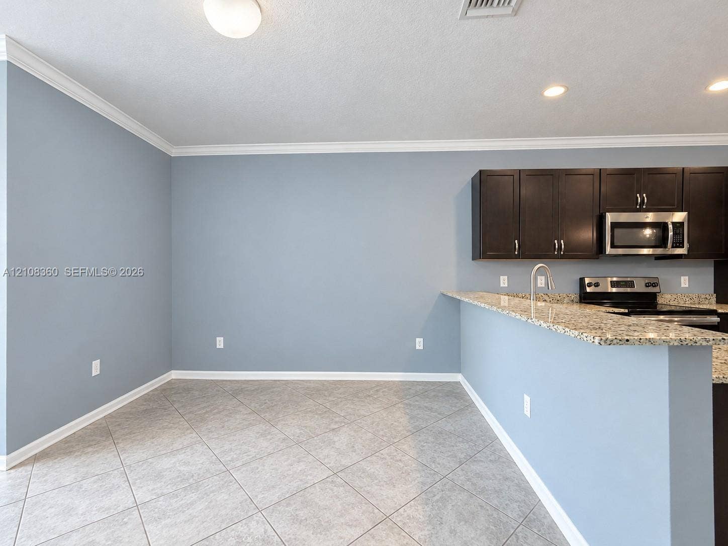 4608 Tara Cove Way, #4608, West Palm Beach, West Palm Beach, FL 33417 Kitchen area featuring dark cabinetry, speckled stone countertops, stainless steel appliances, tile flooring, and crown molding