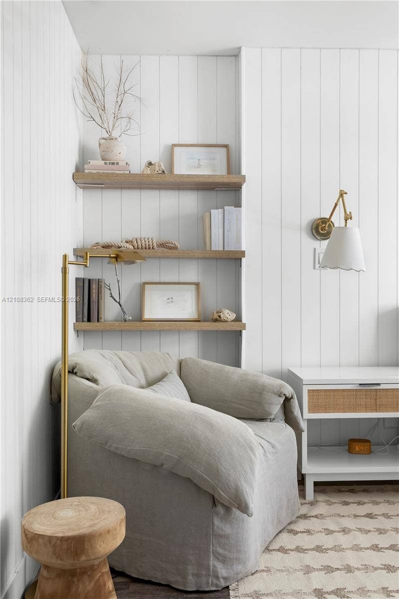 Vertical wood-paneled walls, built-in light-tone wood shelving, and brass swing-arm wall sconce