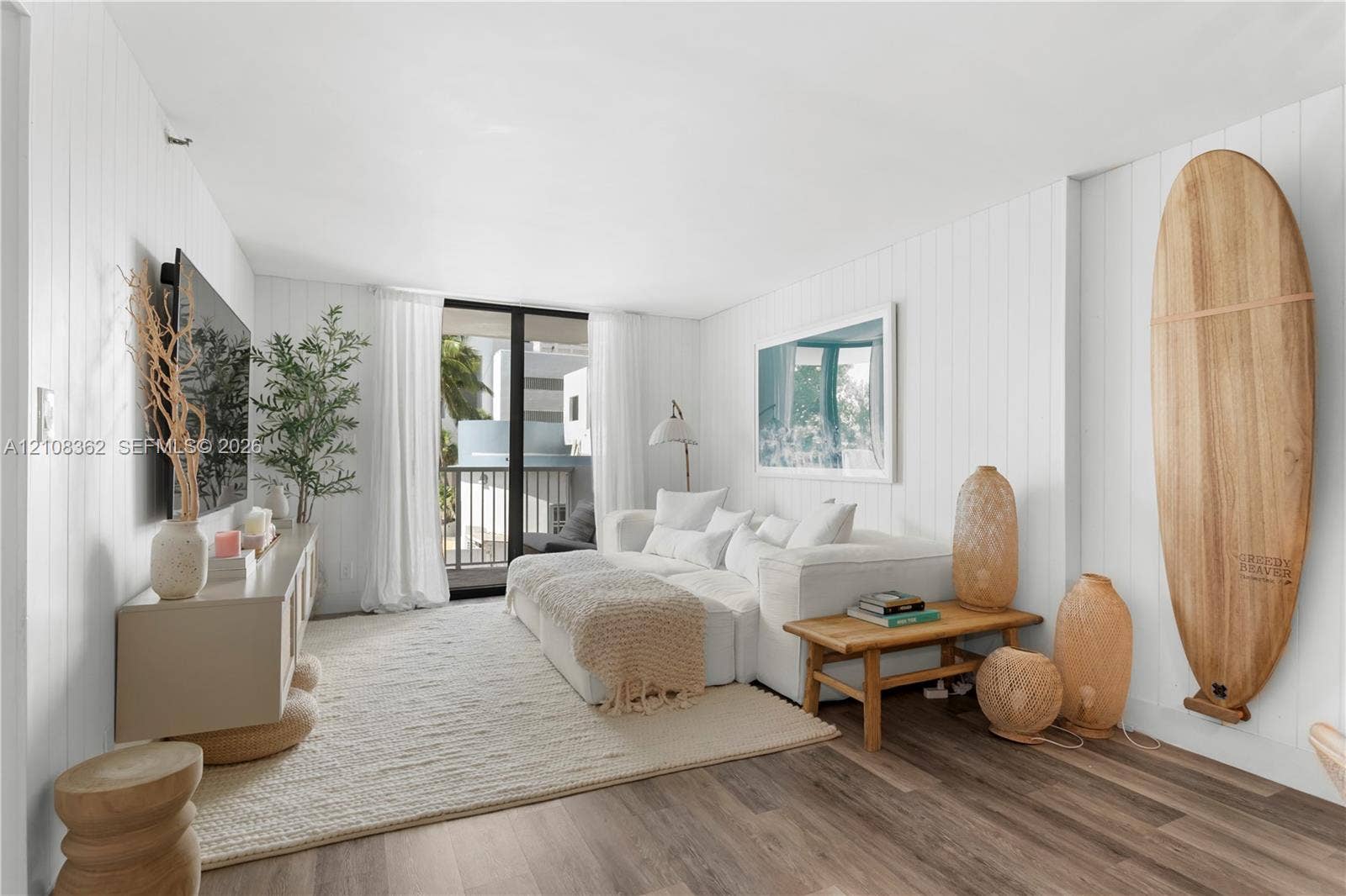 Living area featuring white vertical shiplap wall paneling, wood-finish flooring, and sliding glass doors with balcony access