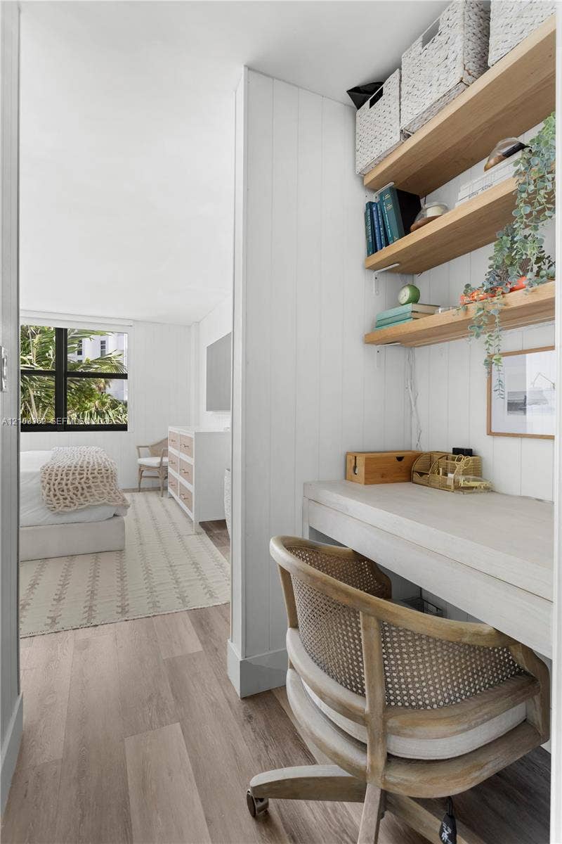 Built-in desk area with wood-finish flooring, vertical panel wall detailing, and open wood shelving