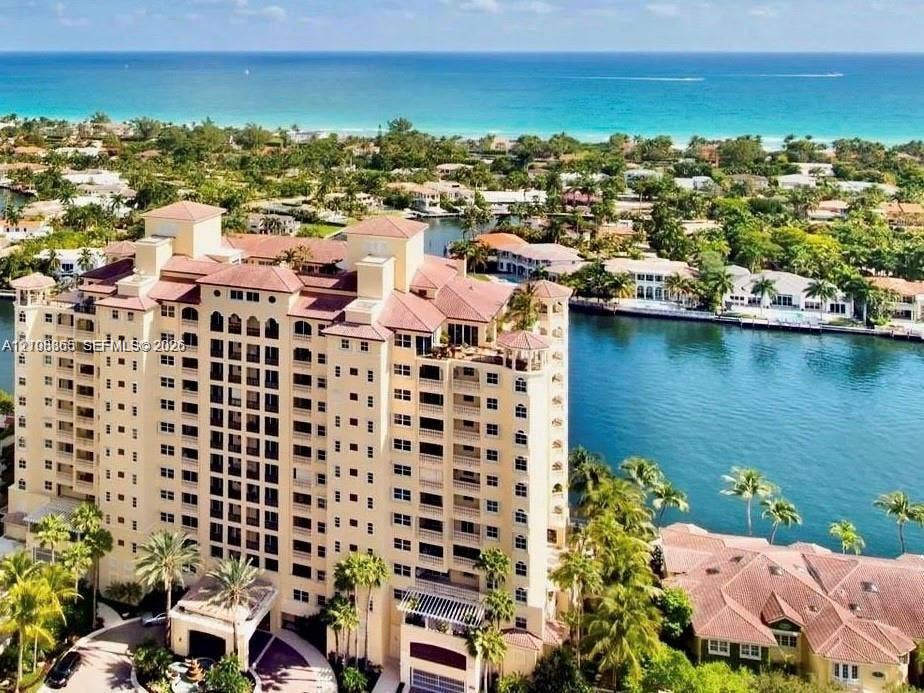 20165 NE 39 Place, #403, Aventura, FL 33180 High-rise building with a multi-level concrete facade, tile roofline, numerous exterior balconies, and a porte-cochere entry, situated on a waterfront lot with canal access