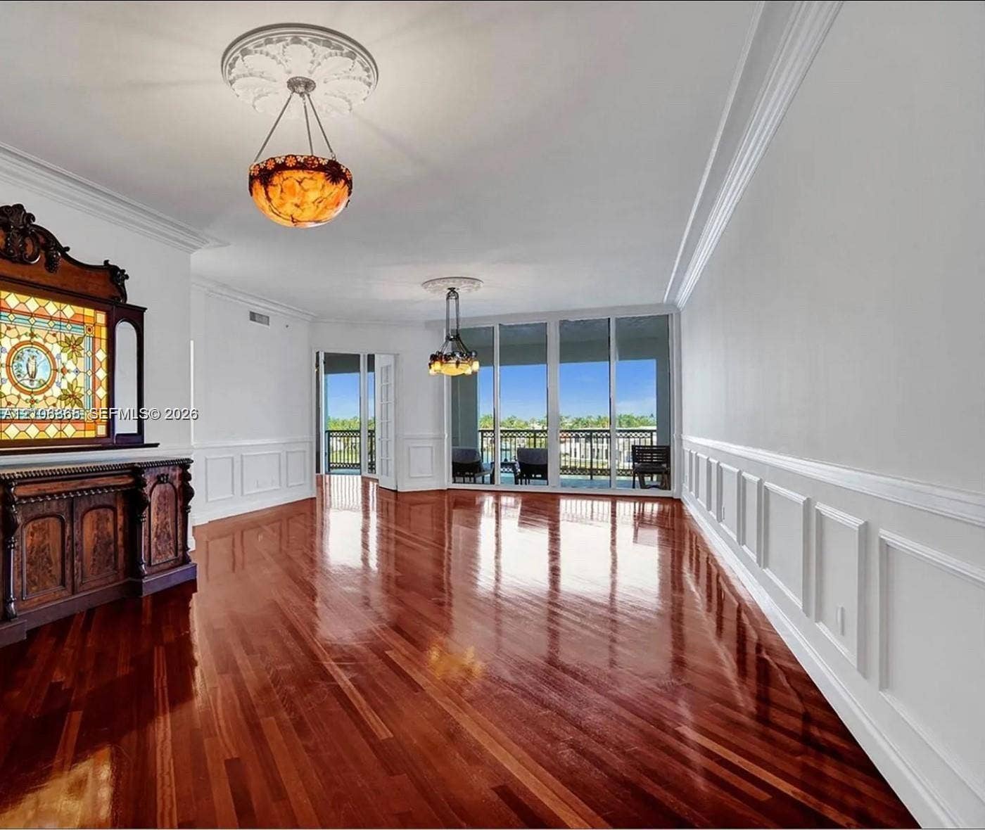 20165 NE 39 Place, #403, Aventura, FL 33180 Polished wood-finish flooring, decorative ceiling medallions, custom wainscoting, built-in stained-glass cabinetry, and floor-to-ceiling sliding glass doors