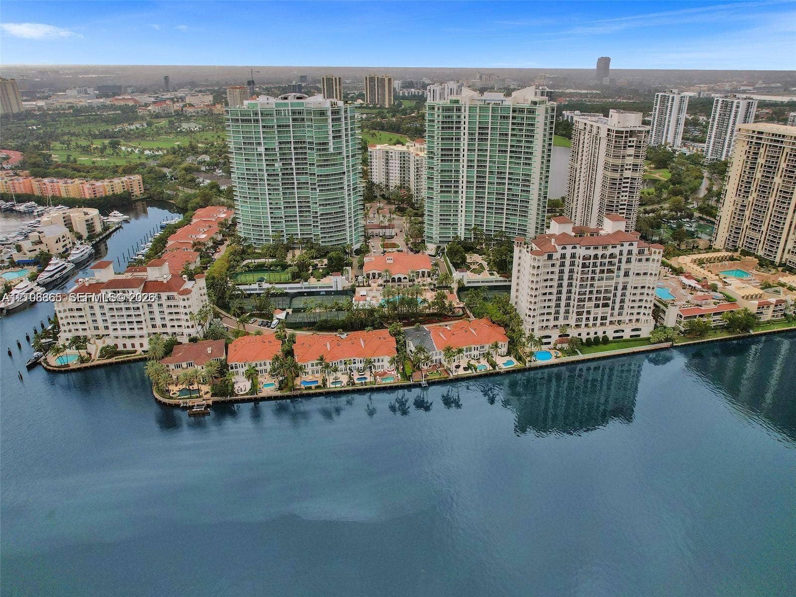 20165 NE 39 Place, #403, Aventura, FL 33180 Waterfront residential complex featuring high-rise towers, multi-level structures with red-tiled roofs, integrated swimming pools, and tennis courts