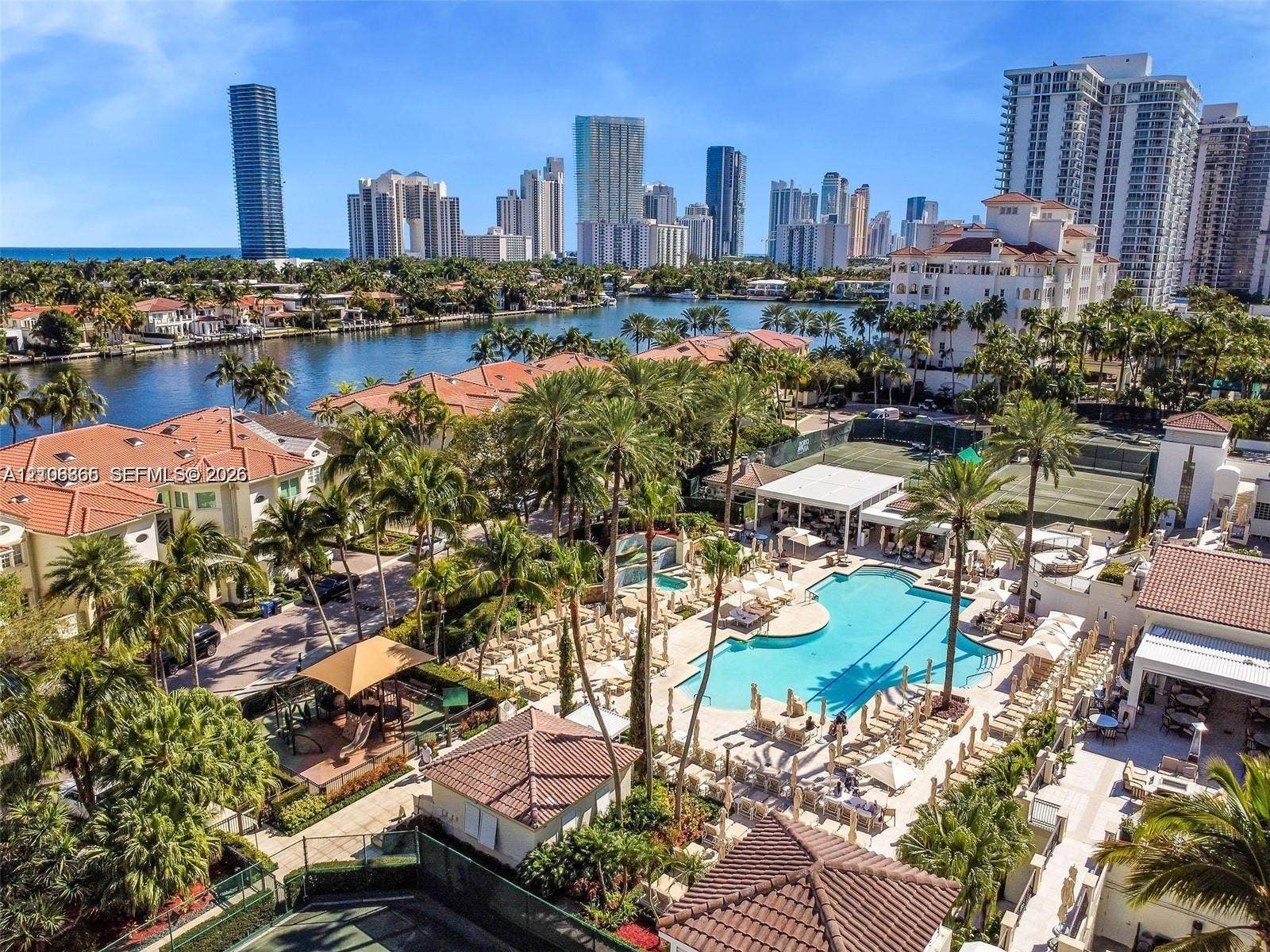 20165 NE 39 Place, #403, Aventura, FL 33180 Waterfront community featuring an expansive swimming pool, professional-grade tennis courts, mature tropical landscaping, and tile-roof architecture