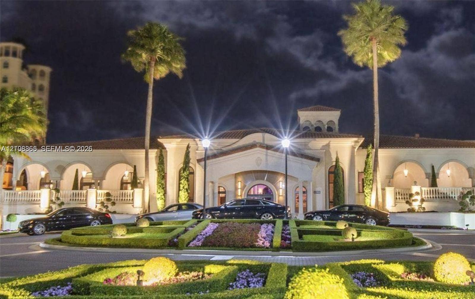 20165 NE 39 Place, #403, Aventura, FL 33180 Mediterranean-style exterior featuring a covered portico, arched loggias, terracotta roof tiles, and manicured ornamental gardens