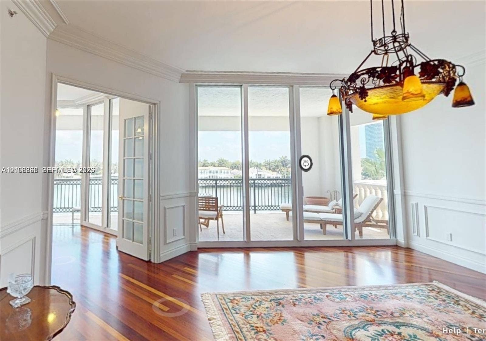 20165 NE 39 Place, #403, Aventura, FL 33180 Room featuring wood-finish flooring, wainscoting, intricate crown molding, a decorative metal chandelier, and floor-to-ceiling glass panel doors
