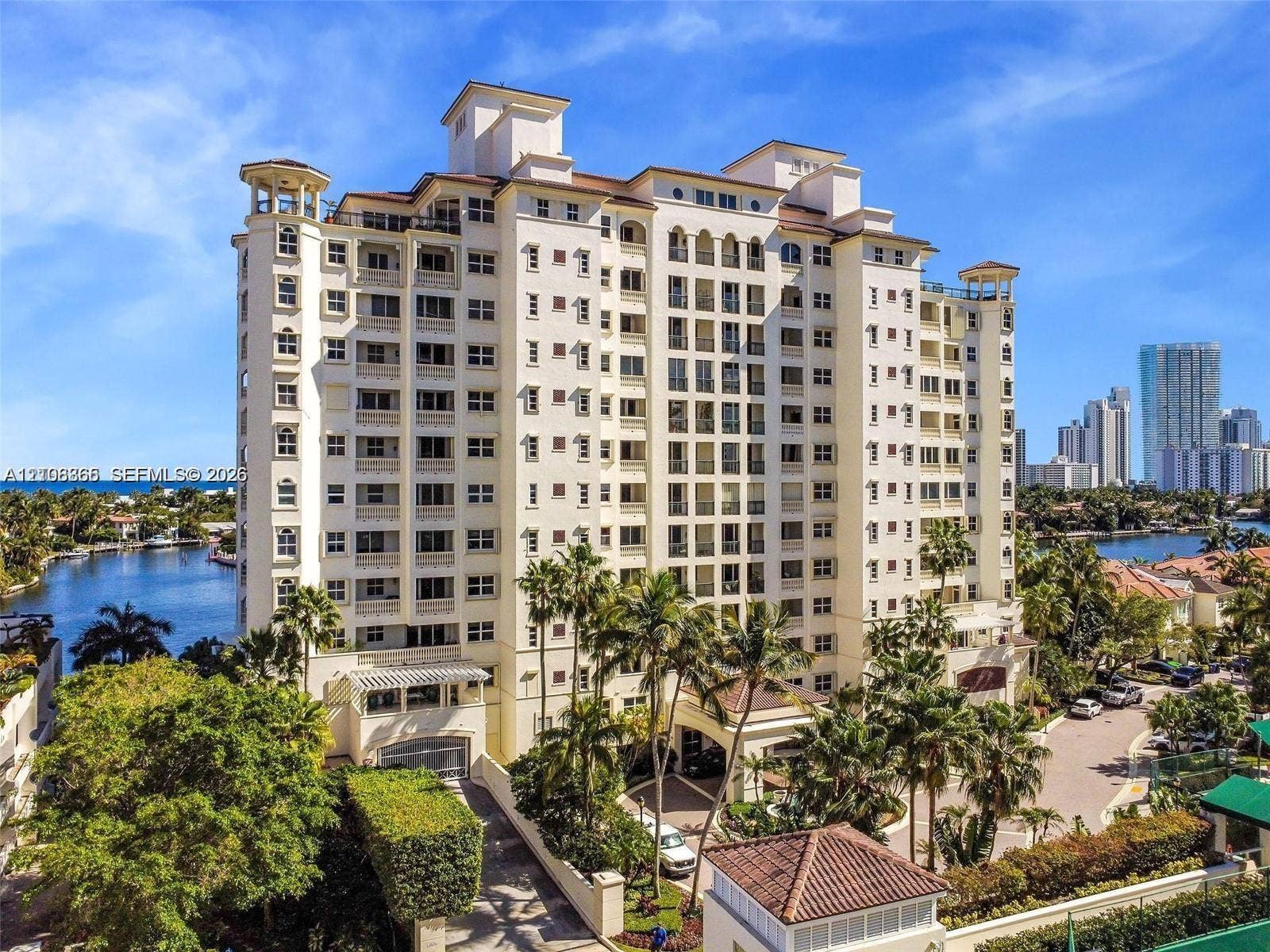 20165 NE 39 Place, #403, Aventura, FL 33180 Mid-rise waterfront high-rise building featuring multi-level balconies, arched architectural detailing, a clay tile roof, and porte-cochre entry