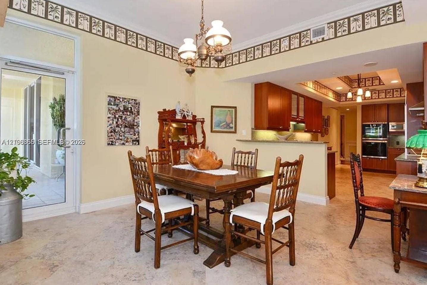 20165 NE 39 Place, #403, Aventura, FL 33180 Open-concept dining area featuring stone tile flooring, stained wood cabinetry, recessed lighting, a decorative chandelier, and a full-glass exterior door