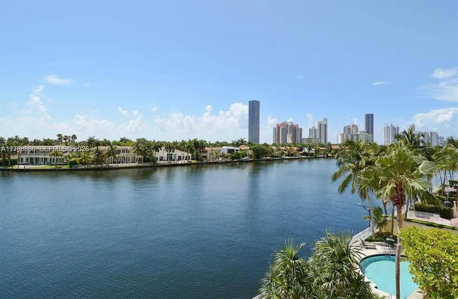 20165 NE 39 Place, #403, Aventura, FL 33180 Waterfront property featuring a canal, private swimming pool, mature palm trees, and coastal skyline horizon