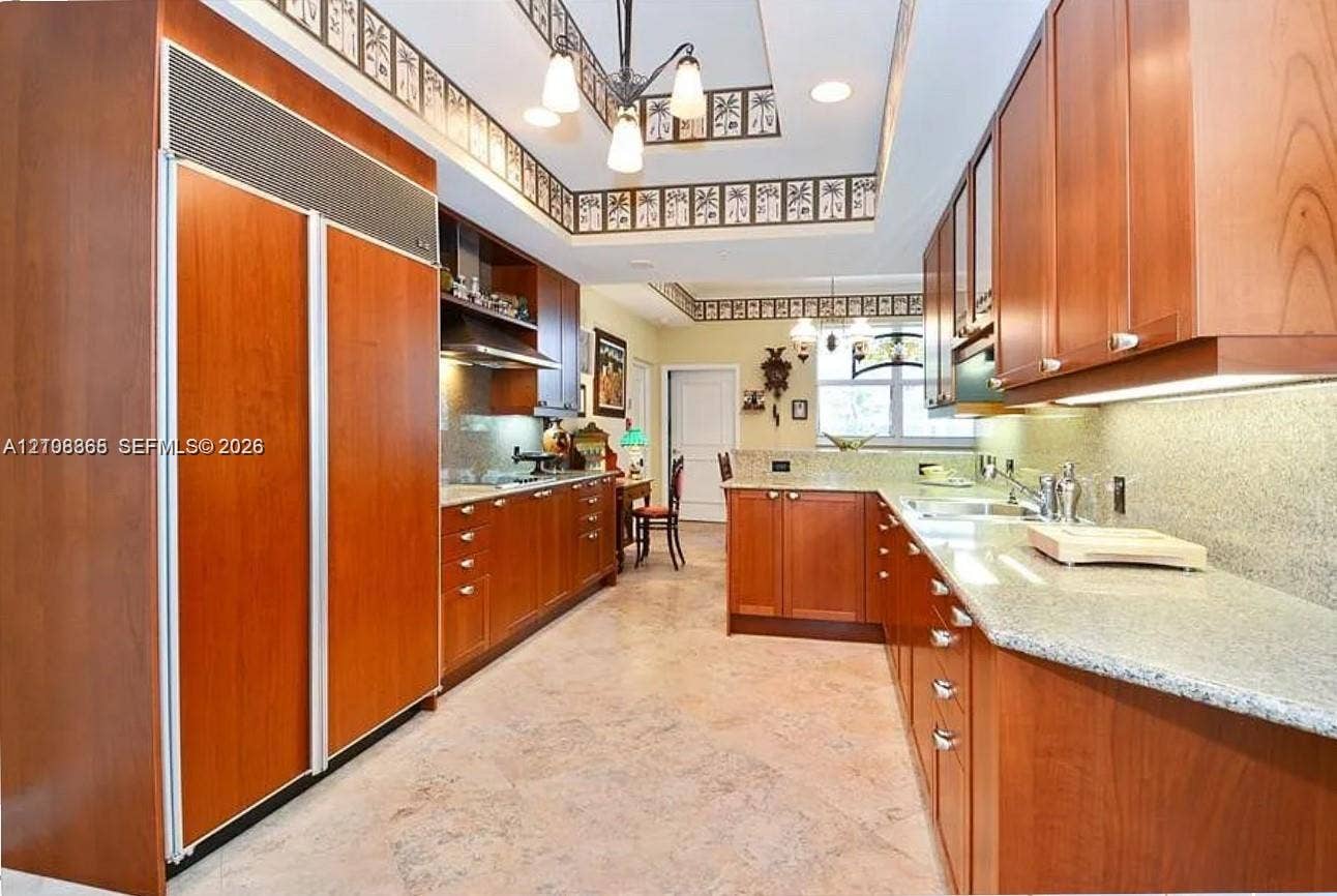 20165 NE 39 Place, #403, Aventura, FL 33180 Kitchen featuring custom wood cabinetry, integrated full-height refrigerator, stone countertops, stainless steel undermount sink, and stone tile flooring