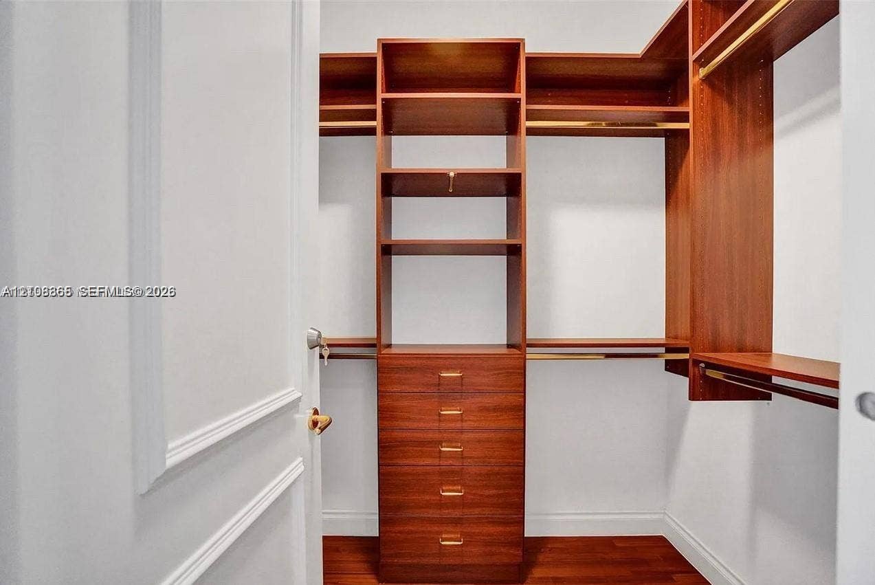 20165 NE 39 Place, #403, Aventura, FL 33180 Custom walk-in closet featuring wood-finish cabinetry, built-in shelving, integrated dresser drawers, and metal hanging rods