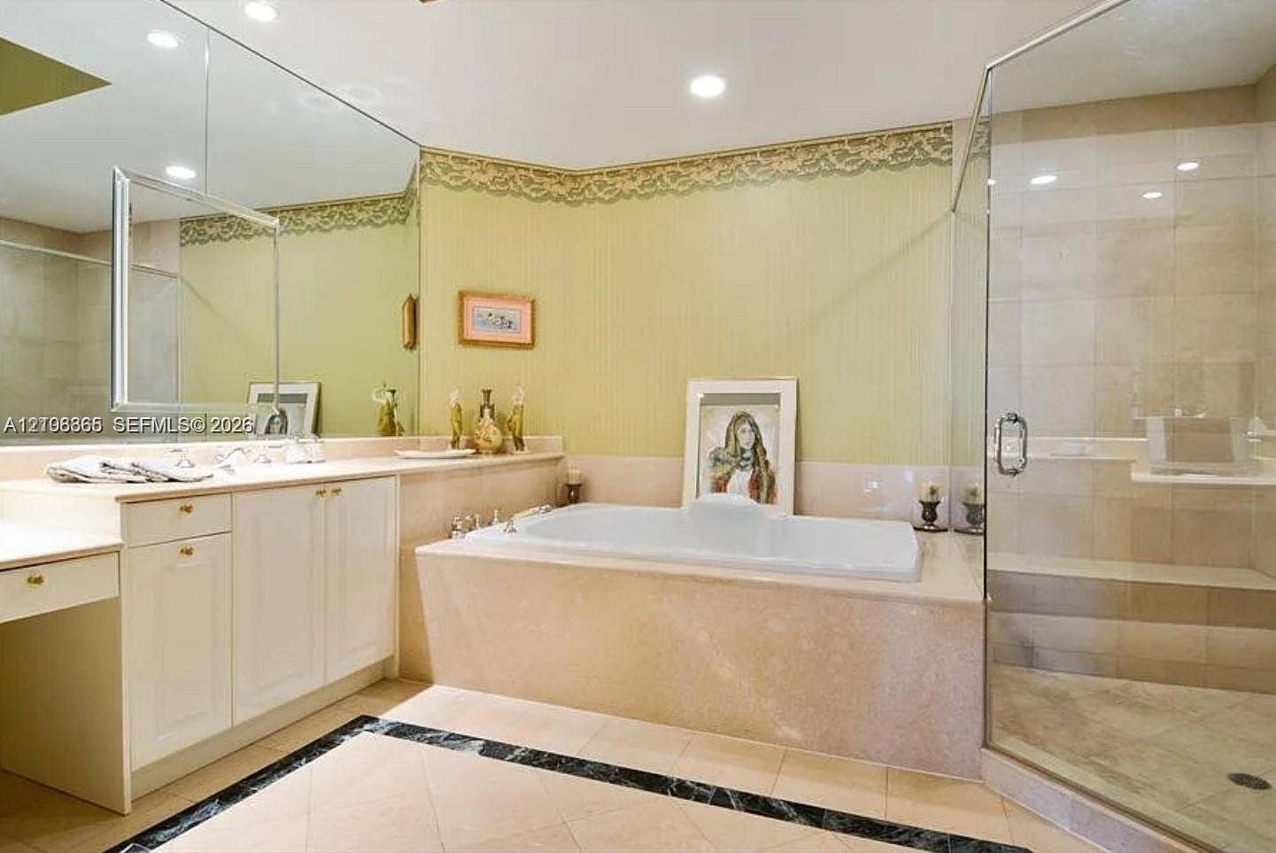 20165 NE 39 Place, #403, Aventura, FL 33180 Bathroom featuring a built-in soaking tub, a frameless glass-enclosed shower with tile surround, white cabinetry, a large wall-mounted mirror, and tile flooring with a decorative border