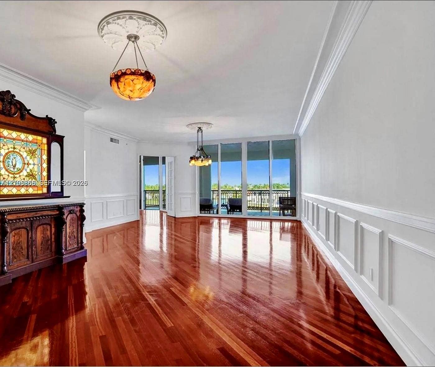 20165 NE 39 Place, #403, Aventura, FL 33180 Polished wood-finish flooring, extensive wainscoting, ornate ceiling medallions, dual hanging light fixtures, and floor-to-ceiling glass sliding doors