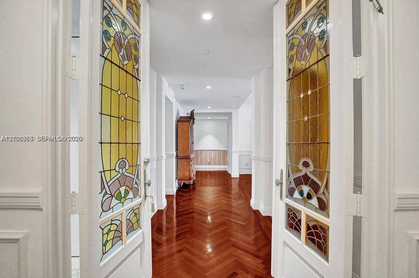 20165 NE 39 Place, #403, Aventura, FL 33180 Double doors featuring decorative stained-glass panels, wood-finish flooring laid in a herringbone pattern, wainscoting, and recessed ceiling lighting