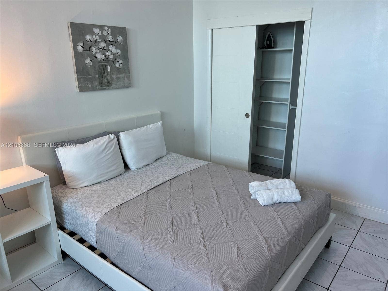 Ceramic tile flooring and a built-in sliding closet with interior shelving